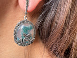 These feminine and classic silver jewelry earrings are truly one of a kind, featuring oval dangle designs measuring 2 inches in length. Adorned with stunning flower-shaped marcasite and oval moss agate gems in a beautiful green hue, these earrings are a perfect gift for a mother-in-law or anyone who appreciates unique and elegant jewelry.