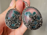 Expertly crafted with flower marcasite and oval moss agate, these sparkly one-of-a-kind silver earrings are both feminine and classic. This must-have accessory is perfect for grandmas looking to add a touch of elegance to their jewelry collection. Experience elegance and uniqueness with our one-of-a-kind silver jewelry featuring eye-catching oval dangle earrings adorned with flower-shaped marcasite and oval moss agate stones in a beautiful shade of green.