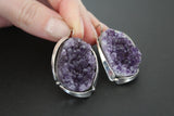 These spectacular, one-of-a-kind earrings are a true testament to the artistry and beauty of nature. At their heart lies a breathtaking amethyst drusy geode, each individual crystal sparkling with a deep, mesmerizing purple hue. The raw, organic texture of the drusy contrasts beautifully with the polished silver sterling 925 that forms the intricate framework, a testament to the skill of the Armenian artisans who meticulously crafted them by hand. Every curve and detail is thoughtfully designed.