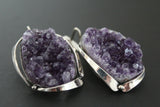 These one-of-a-kind earrings are a breathtaking fusion of natural wonder and artisan skill. Each earring showcases a striking amethyst drusy geode, its surface shimmering with a captivating tapestry of tiny, sparkling crystals. The deep, enchanting purple hue of the amethyst is perfectly complemented by the cool gleam of the silver sterling 925 settings, expertly handcrafted by Armenian artisans. These are not merely earrings - they are wearable sculptures, bearing the hallmark of unique, handmade design.