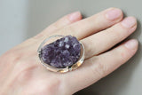 This is more than just jewelry; it's an individual expression. A truly unique handmade ring, it features an exceptionally large amethyst drusy geode, exhibiting a dramatic display of rich purple hues and a texture that begs to be touched. The raw, untamed beauty of the geode is the heart of this piece, embraced by a meticulously crafted setting of sterling silver, stamped with 925. The setting is not merely a functional element; it’s designed to complement and enhance the natural splendor of the stone.
