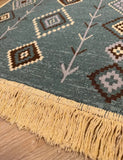 Close-up of a patterned rug with fringes on a wooden floor.