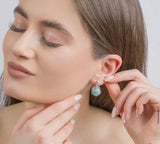 Woman adjusting a earring with a close-up of the ear. The earring is with English lock and the stone is light blue larimar.