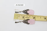 Pink earrings with decorative marcasite  elements on a ruler for scale measurement.