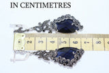 Jewelry with blue stones and silver accents being measured against a ruler, labeled 'IN CENTIMETRES'.