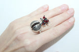 Armenian one of a kind silver ring in a shape of pomegranate with real garnet gemstones on a hand against a white background