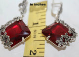 Earrings gemstone with marcasite accents on a measuring tape showing their size.