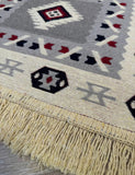 Close-up of a patterned rug with fringes on a wooden floor.