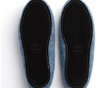 Two blue wool slippers shown from the bottom, featuring black suede soles with gold contrast stitching and a visible 'WOOLS' logo.
