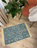 Decorative rug with geometric Armenian pattern on a wooden floor, next to a plant and chair.