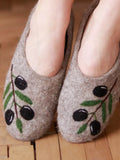 Merino wool gray slippers with olive design on a woody floor