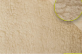 Close-up of a beige textured fur merino wool blanket surface with two rounded text boxes and a circular inset showing the pile texture. 