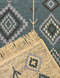 Close-up of a patterned rug with geometric designs and fringed edge.
