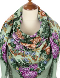 Side view of a woman wearing a soft merino wool scarf in beige, decorated with large red and pink roses and classic fringed borders.