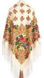 An elegant, oversized ivory woolen palantine designed in a heritage Slavic floral aesthetic. The warm, thick fabric displays a colorful arrangement of pink, yellow, and orange blossoms, with long flowing fringes emphasizing its large, blanket-like size.