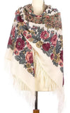 A multicolored floral patterned merino wool scarf in Slavic traditional style draped around a mannequin, predominantly white with touches of pink and other colors, with fringe detailing.