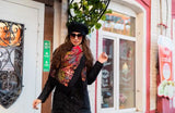 A woman modeling a classy Slavic-style merino wool shawl, draped over her head in deep red paisley and cascading into a black floral pattern.