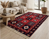 Armenian red woven carpet with traditional Artsakh ornaments with fringe near a beige sofa and wooden small modern table.
