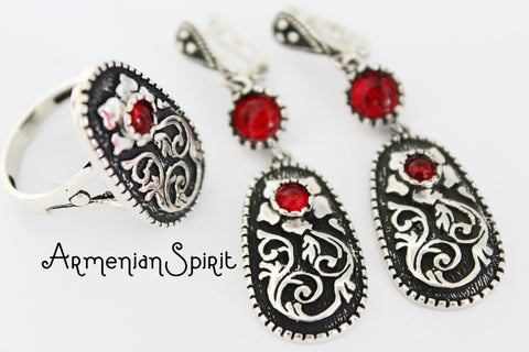A set of sterling silver jewelry, featuring floral long earrings and a ring, with red garnet stones. The jewelry is displayed against a white background with the Armenian Spirit brand visible. A celebration of ethnic artistry in sterling silver. This collection is from the best Armenian silver store, known for its cultural touch. Every item is delivered directly from Armenia, rich with tradition. The team is reliable and experienced in global shipping. 