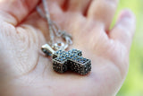 Armenian bold square cross with stones on a woman hand with chain.