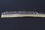 A wide 925 sterling silver cuff bracelet featuring the Armenian alphabet engraved around the band, styled for a woman's  and man`s hand, from the Armenian Spirit brand on a yellow ruler showing its length