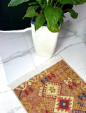 Small patterned rug on a marble floor with a potted plant in the background