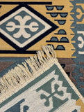 Close-up of a patterned  Armenian rug with geometric designs and cotton fringes.