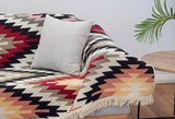 Patterned Armenian cotton rug with fringes in red and beige draped over a sofa with a pillow in a living room setting.