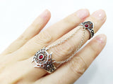 A double silver ring with red quartz stones, positioned on a person's hand to showcase its fit and design.