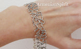 A wide 925 sterling silver cuff bracelet featuring the full Armenian alphabet intricately engraved around the band, styled on a woman's hand, from the Armenian Spirit brand.