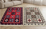 Two rectangular patterned area Armenian rugs displayed side by side on a light wood floor in a living room setting, with a beige sofa and white curtains visible in the background.
