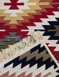 Close-up of a patterned rug with geometric design and fringes.