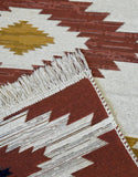 Close-up of a patterned rug white and brown with geometric design and fringes.