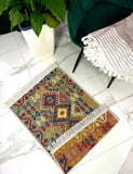 Small colorful  Armenian traditional rug on a tiled floor with a plant and chair in the background