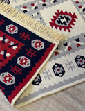 Close-up of a patterned Armenian rug with geometric designs on a wooden floor.