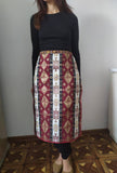 A woman wearing a traditional Armenian taraz apron in burgundy, navy, and beige with national patterns and ornaments.