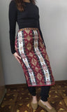 A woman wearing an Armenian taraz apron in Vaspurakan and Kars inspired style, with traditional ornaments and patterns in burgundy and beige.