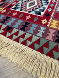 Close-up of a patterned rug with fringes on a wooden floor