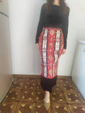 A tall woman wears Armenian traditional long rectangle taraz apron in red and white wth ethnic ornaments and patterns.