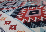 Close-up of a patterned fabric with geometric designs in red, blue, and white.
