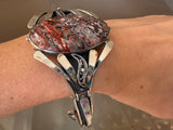 Vintage Silver bracelet with a red and brown stone on a wrist against a neutral background