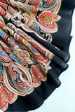 Black and red merino wool shawl with colorful paisley patterns on a white background