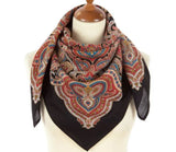 Colorful red and black paisley patterned woolen scarf on a mannequin with a white background