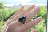 A black stone ring with marcasite accents on a sterling silver 925 band, displayed on a person's hand.