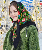 A woman wearing a beautiful Slavic shawl made of 100% merino wool. The natural sheep wool has a deep black base adorned with red and goldish yellow peony flowers.