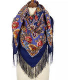 Colorful floral-patterned scarf with fringes on a mannequin against a white background