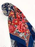 Floral patterned scarf with blue border and red large flowers with silky blue fringe on a white background