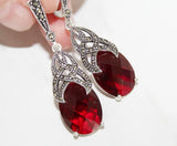 Red faceted teardrop earrings with silver and marcasite detailing on a white background