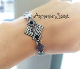 A sterling silver Armenian bracelet with black onyx gemstones and a tribal geometric design, displayed on a person's wrist.