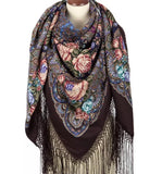 Colorful peach and turquoise floral and paisley patterned brown scarf with fringes on a mannequin against a white background